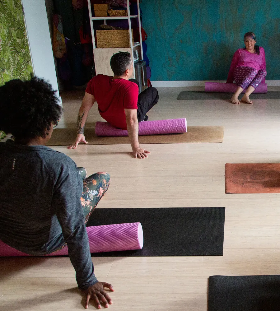 Jo is leading a pilates workshop. There is a man and a woman in the foreground on a foam roller.