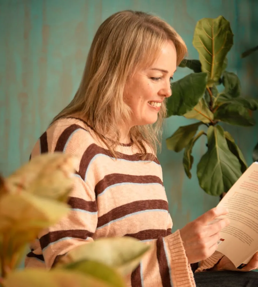 Jo is reading a book surrounded by plants